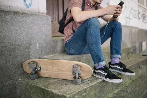 Cropped man relaxing on stairs with phone and skateboard — Stock Photo, Image