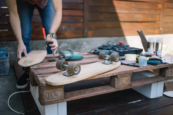 Beschnittener Mann montiert Skateboard auf Tisch in Werkstatt — Stockfoto