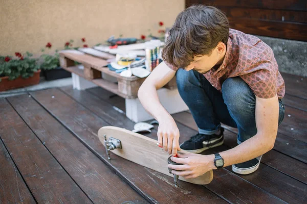 Brünetten Mann platziert Skateboard-Räder im Freien — Stockfoto