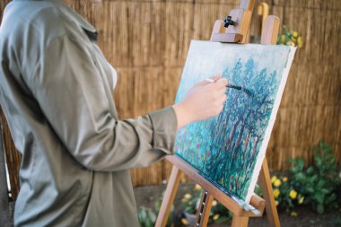 Kesilmiş kadın tuvale resim çiziyor.