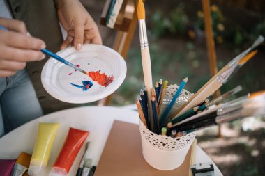 Kırpılmış sanatçı açık hava stüdyosunda boya karıştırıyor.