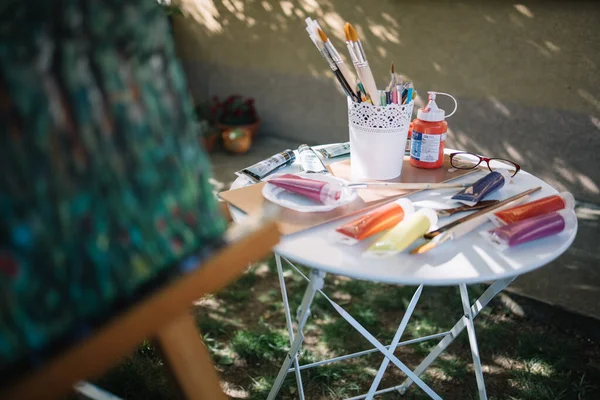 Mesa com tubos de pintura e escovas ao ar livre — Fotografia de Stock