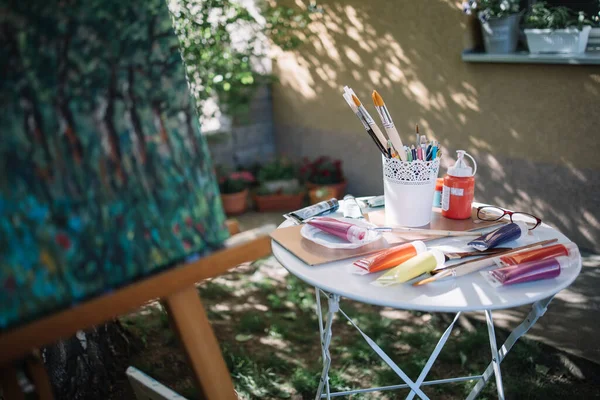 Mesa com tubos de pintura e escovas ao ar livre — Fotografia de Stock