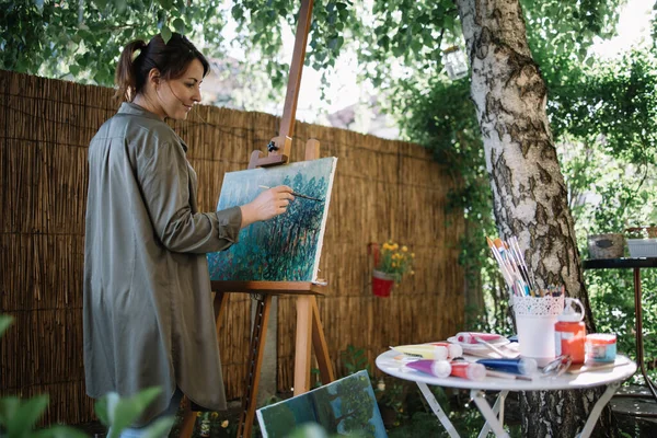 Jovem bela mulher pintando um quadro sobre tela — Fotografia de Stock