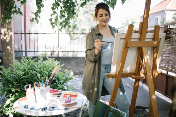 Artista feminina usando pincel enquanto pinta no quintal — Fotografia de Stock