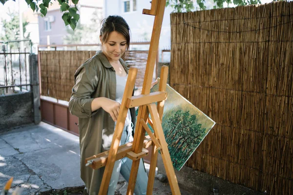 Artista feminina em pé no quintal enquanto segurava tela pintada — Fotografia de Stock