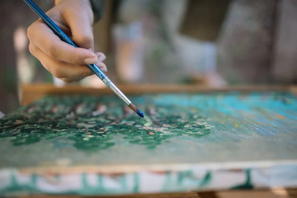 Närbild av hand hålla används färg borste över målning — Stockfoto
