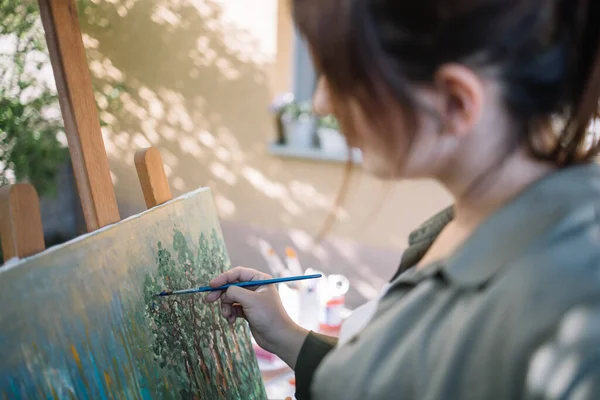 Mujer morena borrosa pintando cuadro en el patio — Foto de Stock