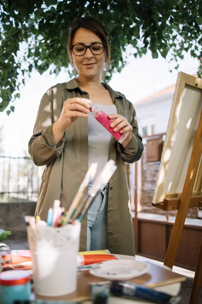 Mujer artista de pie en un estudio al aire libre con trípode — Foto de Stock