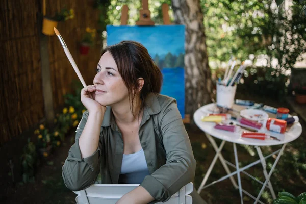 Portrait of woman holding paintbrush and dreaming — Stock Photo, Image