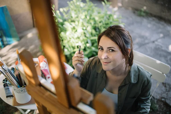 Portret van vrouw met penseel zittend achter wazig staan — Stockfoto
