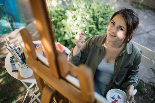 Sonriente chica sosteniendo pincel y pintura al aire libre — Foto de Stock