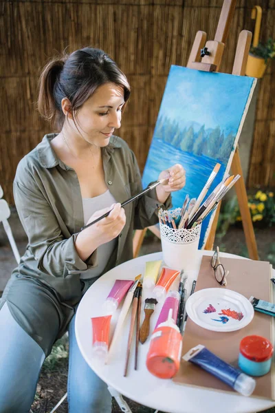 Retrato de mulher olhando pincel no estúdio de arte do jardim — Fotografia de Stock