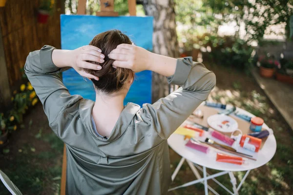Vista posterior de la mujer haciendo moño de pelo en un patio trasero con pintura — Foto de Stock