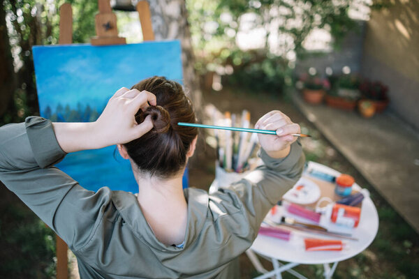 Девушка делает булочку с помощью кисти перед раскрашенным холстом