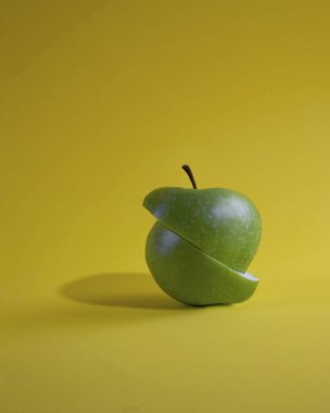 Sarı arkaplanda yeşil elmayı kes