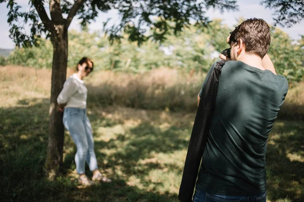 Widok z tyłu mężczyzna robi zdjęcia dziewczyna w park — Zdjęcie stockowe