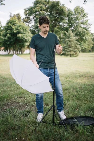 Muž umísťující difuzor deštníku do stativu pro focení — Stock fotografie