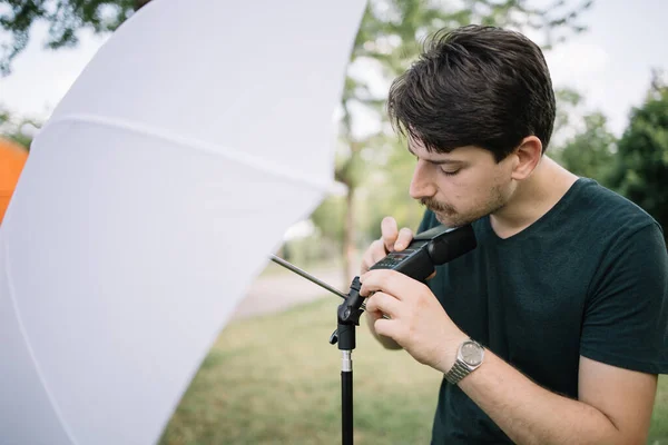 Fotograf připravuje venkovní fotostudio při připojení deštníku difuzoru — Stock fotografie