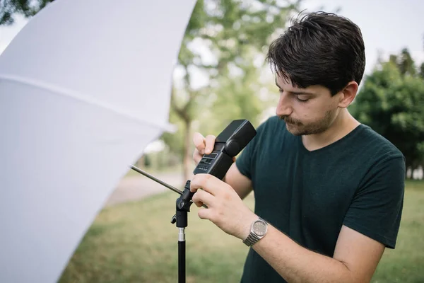 Zaostřený muž nastavuje záblesk deštníku na lehký stojan — Stock fotografie