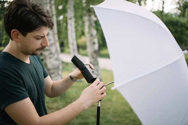 Muž fotograf nastavení profesionální světlo na stativ s deštníkem — Stock fotografie