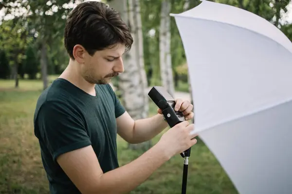 Portrét muže, jak nastavuje záblesk na světelný stojan — Stock fotografie