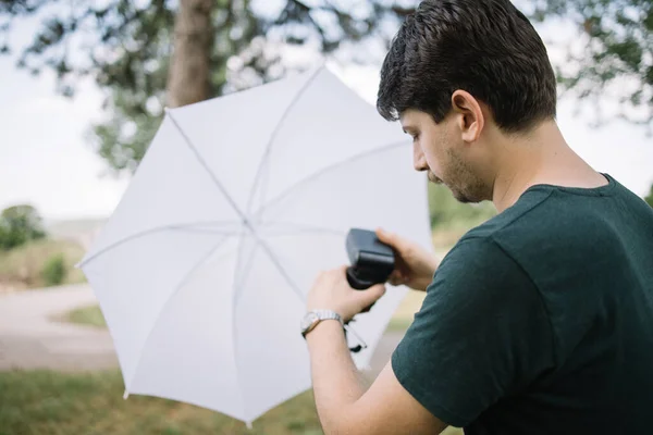 Fotógrafo definir luz de flash em um tripé com guarda-chuva — Fotografia de Stock