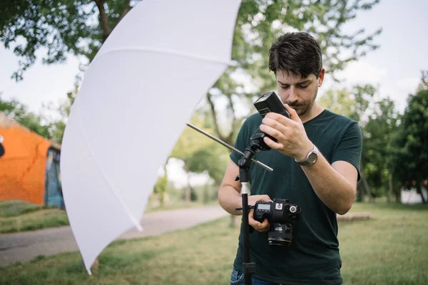 カメラを持ちながらフラッシュライトを設定する男性写真家 — ストック写真