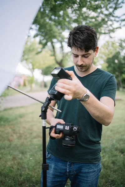 Portrét muže, jak se dívá do kamery a nastavuje blesk — Stock fotografie