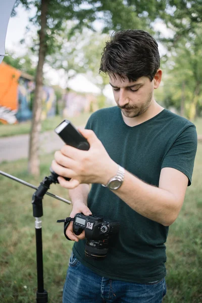 Kameralı bir adam açık hava fotoğraf çekimi için hazırlanıyor.