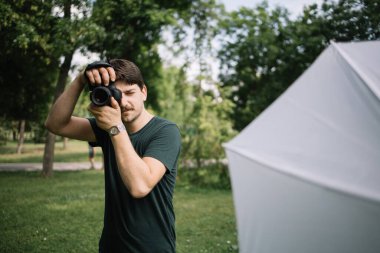 Adam parkta kamera kullanarak fotoğraf çekiyor.