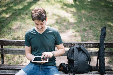 Tabletle bankta oturan adamın ön görüntüsü