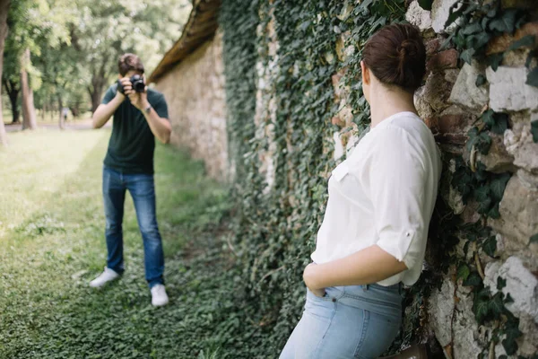 Размытый мужчина с профессиональной камерой фотографирует девушку — стоковое фото