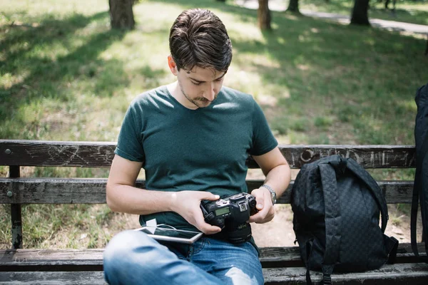 Fotograf kontrolující focení fotografií při sezení na lavičce — Stock fotografie