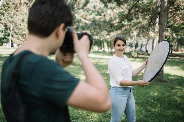 Visszapillantás a férfi fotózás ülésen lány, aki gazdaság reflektor — Stock Fotó