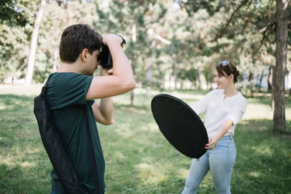 Человек с камерой фотографирует размытую девушку с рефлектором — стоковое фото