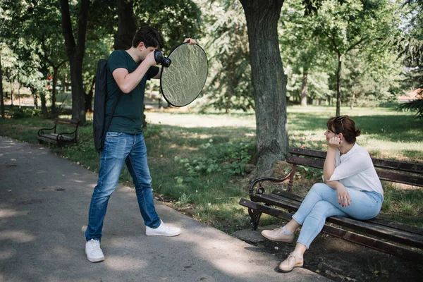 Fotograf trzymający kamerę i reflektor robiący zdjęcia w parku Zdjęcie Stockowe