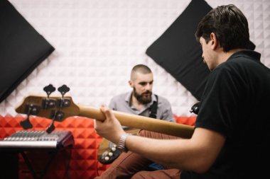 Bulanık adamın önünde gitar tutan adamın arka planı.