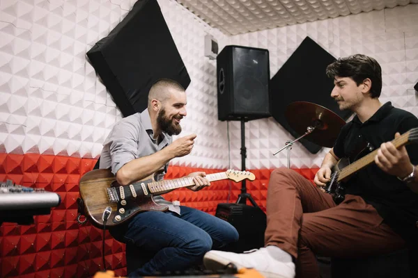 Usmívající se kytaristé nacvičují ve zvukotěsném studiu — Stock fotografie