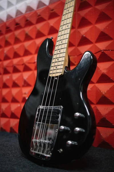 Černá elektrická kytara opřená o zeď ve zvukotěsném studiu — Stock fotografie