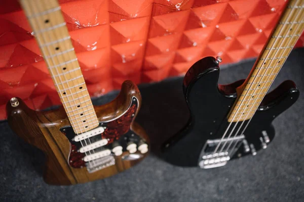 Dvě ořezané kytary opřené o červenou zeď — Stock fotografie