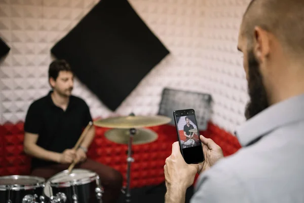 Мужчина фотографирует с помощью телефона барабанщика, играющего на барабанах — стоковое фото