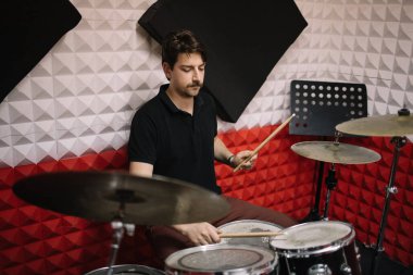 Stüdyoda prova sırasında davul çalan davulcu.