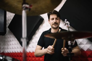 Müzik stüdyosunda oturup davul çalan adamın portresi.