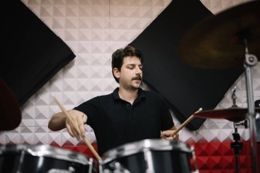 Erkek sanatçı davul çalarken müzik kaydediyor