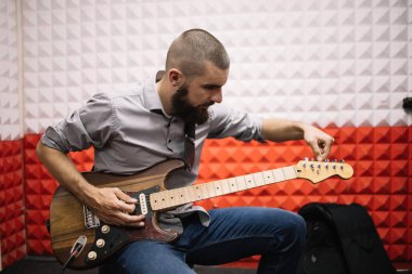 Rock müzisyeni müzik stüdyosunda gitar akort ediyor.