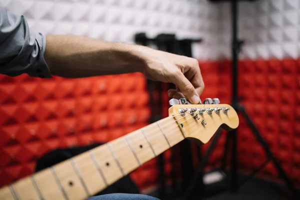Stüdyoda gitar çalan bir erkek müzisyenin eli.