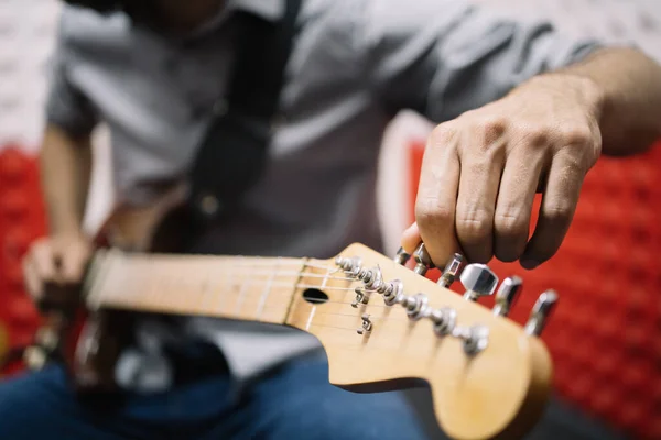 Музыкант настроил гитару в музыкальной студии — стоковое фото