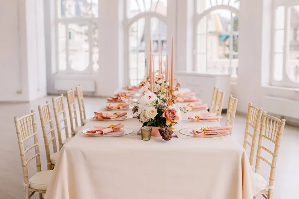 Wedding decoration table in the hall, floral arrangement. In the style vintage. Decorated dining table with flowers for guests and newlyweds, in peach-pink & pastel color. Beautiful table setting.