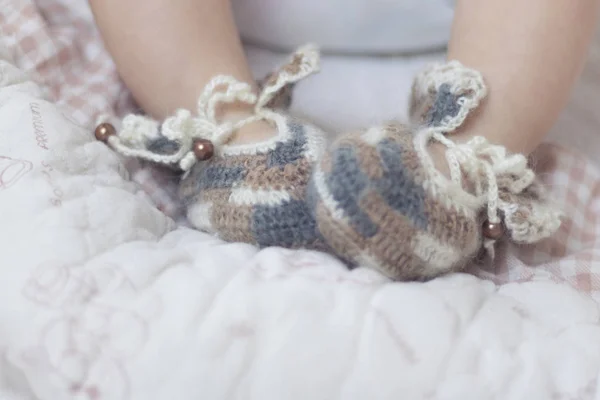 Les pieds de bébé nouveau-nés se rapprochent en chaussettes brunes tricotées sur une couverture blanche. Le bébé est dans le berceau. . — Photo